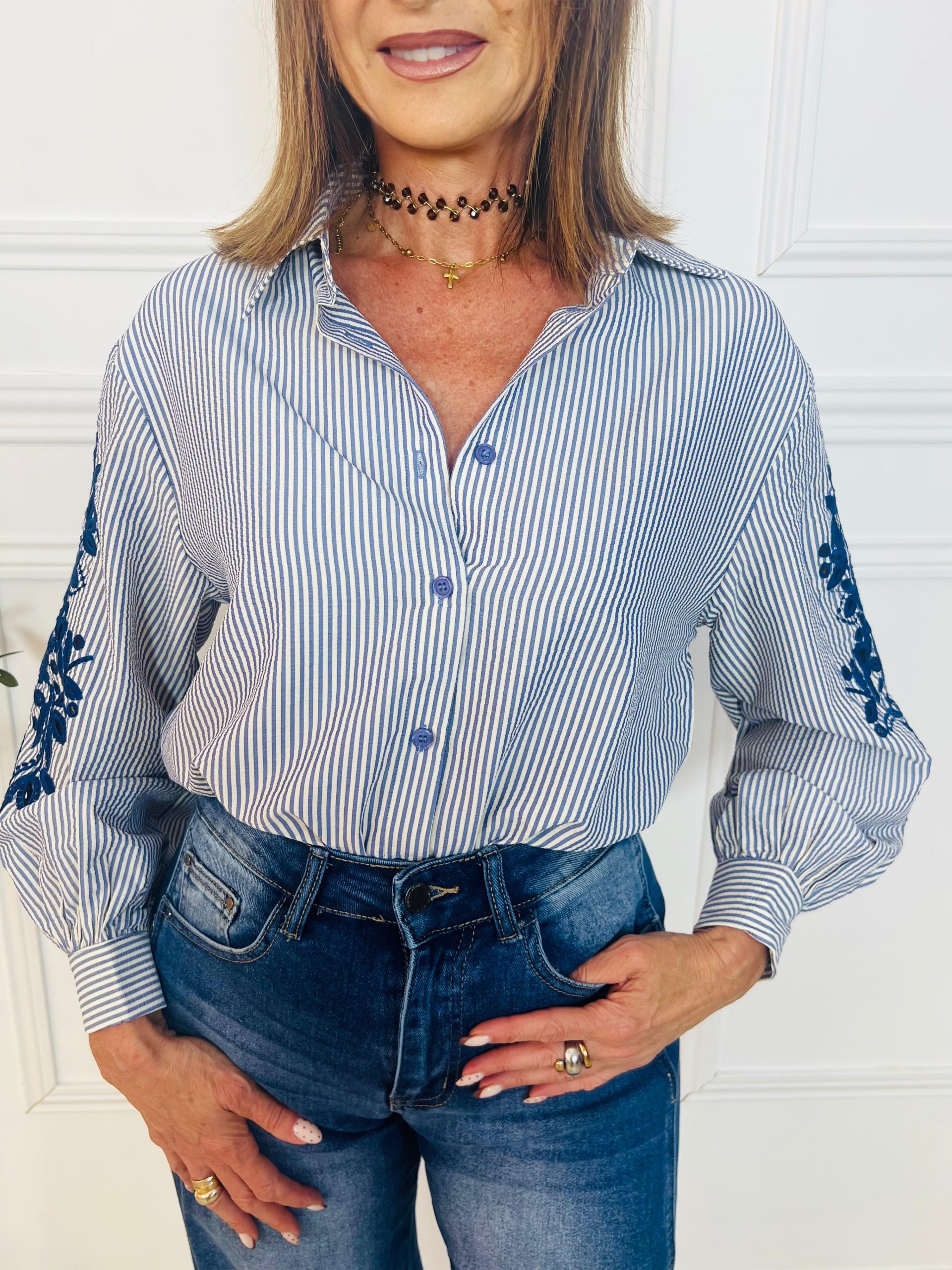 Camisa rayas de cuello solapa y manga larga. Cierre frontal con botones. Detalles bordados en las mangas. Oliva Valencia