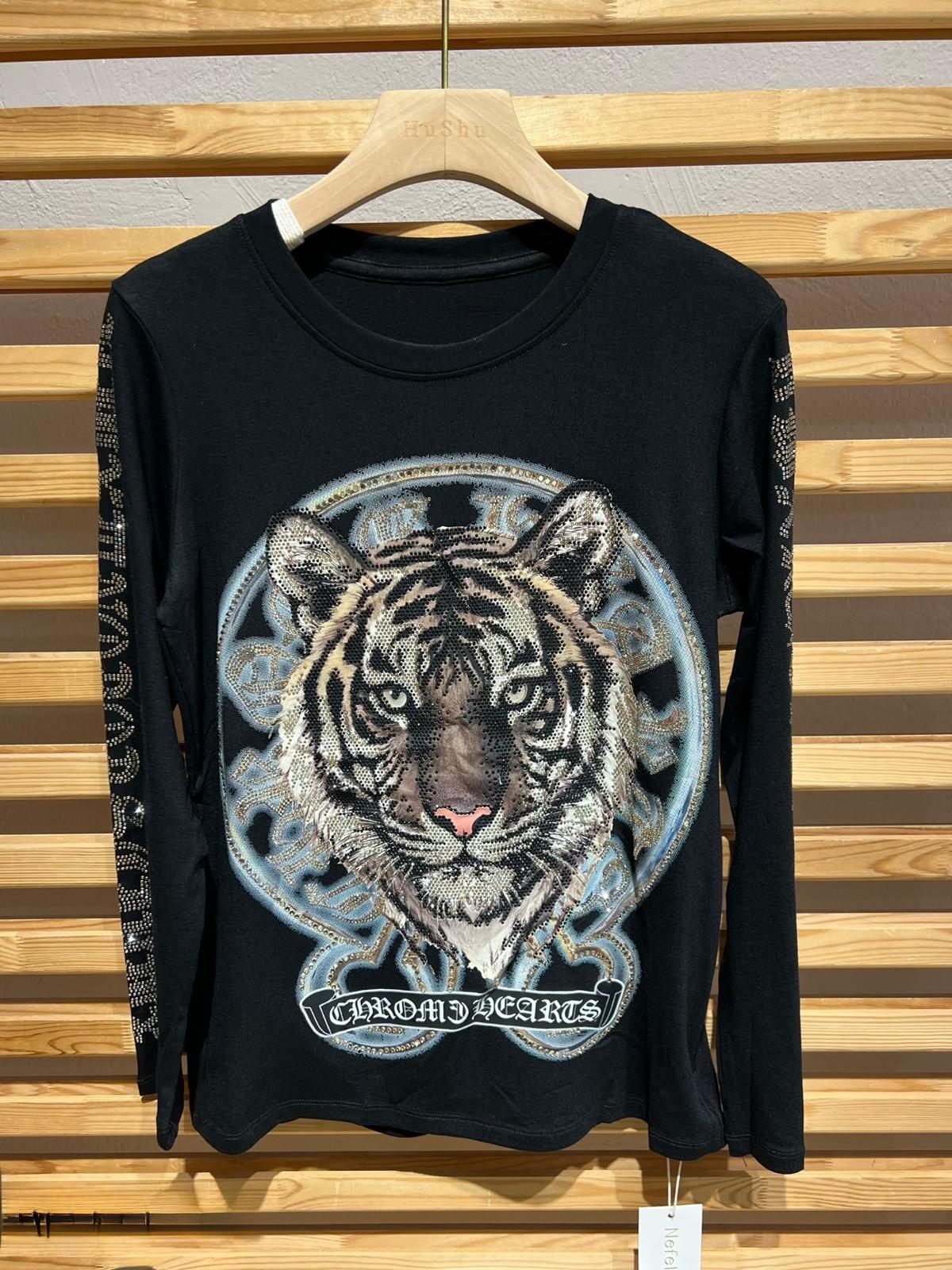 Suéter de punto negro talla unica con una llamativa ilustración frontal de la cara de un tigre, que aporta carácter y un estilo moderno al diseño. Confeccionado en tejido suave y confortable, es ideal para el día a día. Su corte cómodo y versátil lo convierte en una prenda fácil de combinar, perfecta para dar un toque original y atrevido a cualquier look.